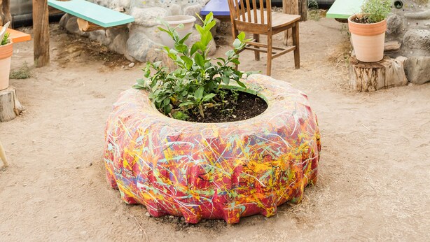 A geodesic dome structure with a wooden table, chairs, and potted plants inside.