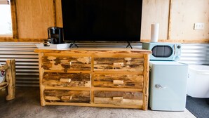A wooden cabinet with drawers, a television, a coffee maker, and a microwave.