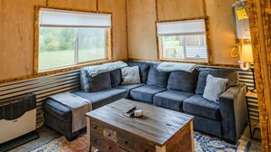 A room with a ceiling fan, a sectional sofa, a wooden coffee table, and a patterned rug.