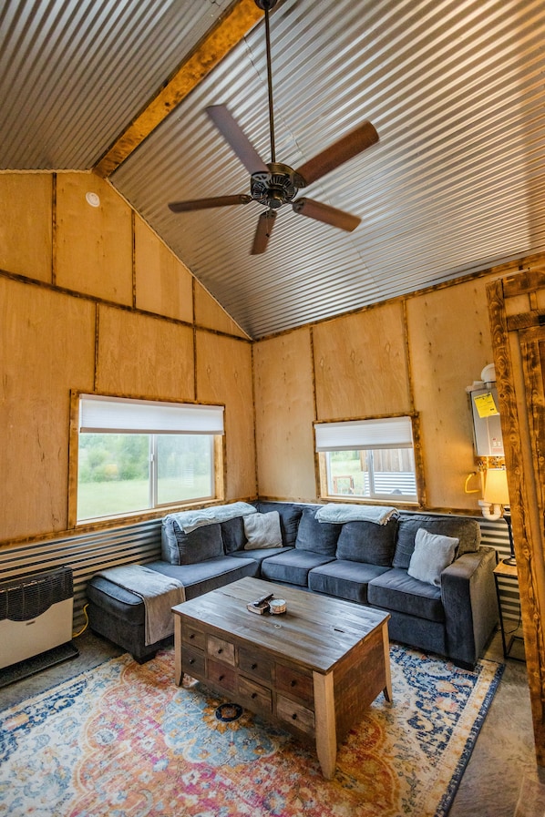 A room with a ceiling fan, a sectional sofa, a wooden coffee table, and a patterned rug.