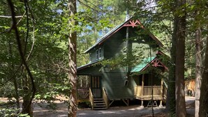 Een rustieke hut met een veranda en een kleine trap naar de ingang.