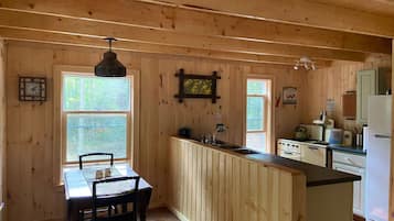 Ein Holzblockhaus-Innenraum mit Küchenzeile, Esstisch und Stühlen.