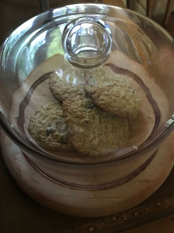 A clear glass dome over a wooden serving dish with cookies.