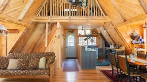 Un interior acogedor de madera con un dormitorio en entrepiso, una zona de comedor y una cocina.
