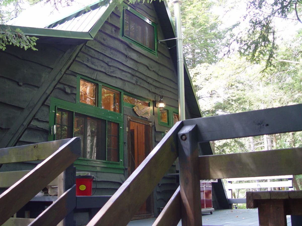 Una cabana rústica amb façana de fusta, una escala que mena a l'entrada i un petit porxo.