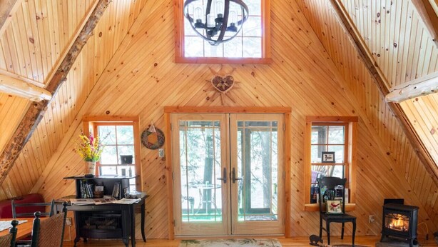 Un interior acogedor de madera, con techo alto, chimenea y comedor.