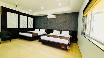 A hotel room with two beds, a ceiling fan, a green chair, and a window with curtains.