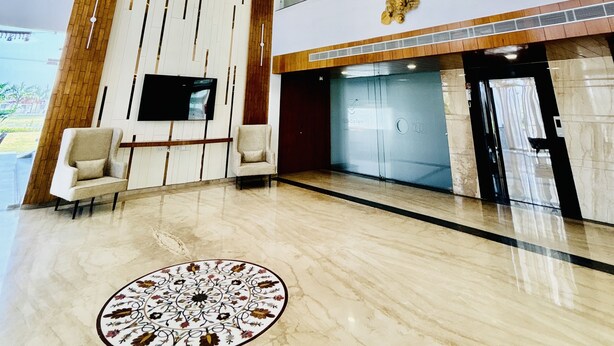 Un vestíbulo moderno con candelabro, televisor de pantalla plana y mostrador de recepción.