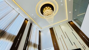 Un interior moderno con una araña central, paneles de madera y un dise ño geométrico en el techo.