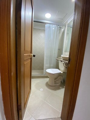A bathroom with a toilet, shower, and a mirror. - Apto 2 hab piso alto (Cartagena)