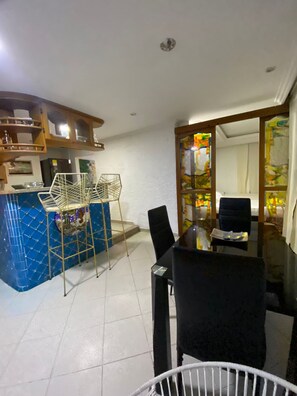 A dining area with a blue tiled wall, a glass-top table, and black chairs. - Apto 2 hab piso alto (Cartagena)