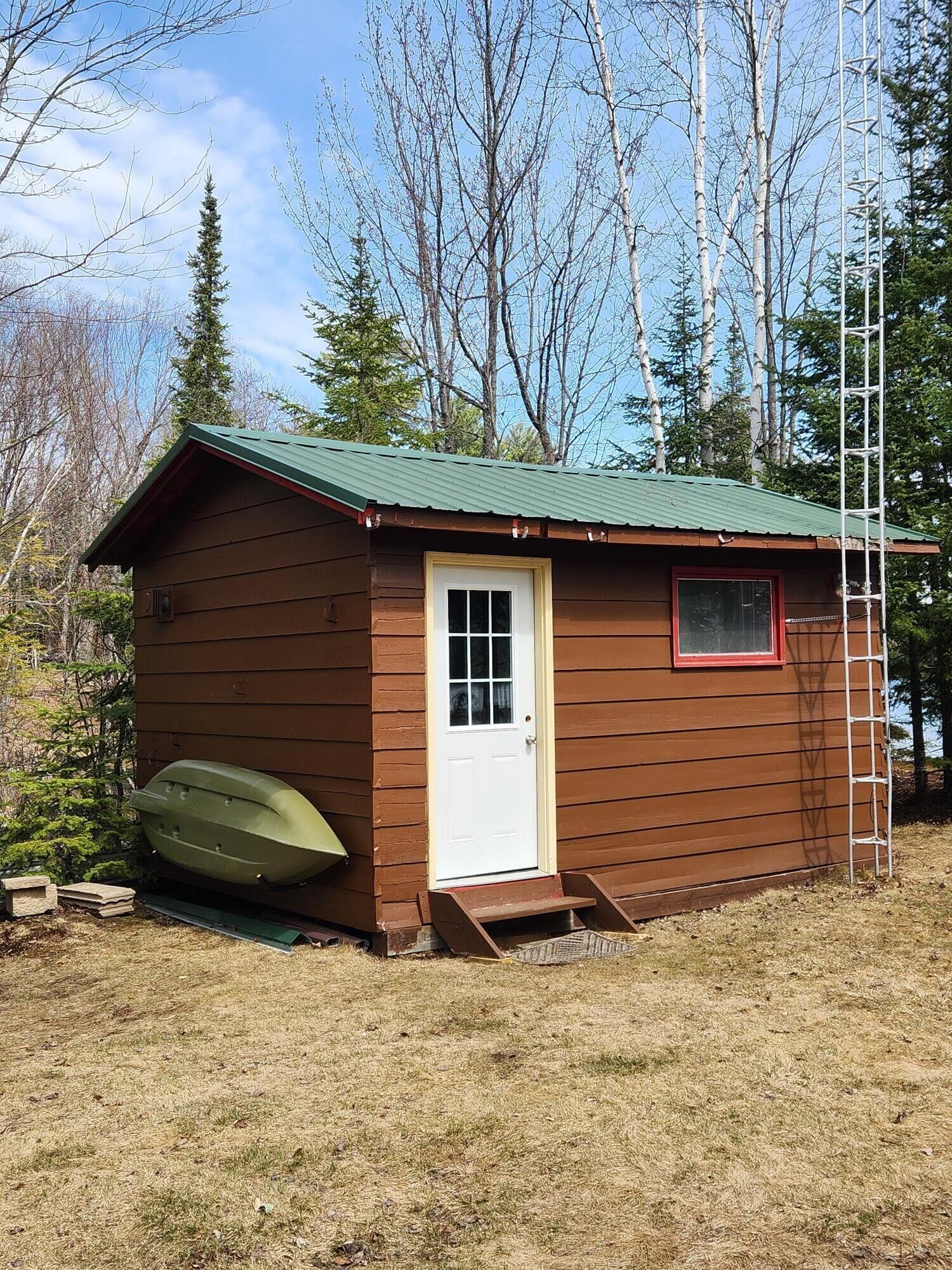 A small wooden cabin with a green roof, a white door, and a window.