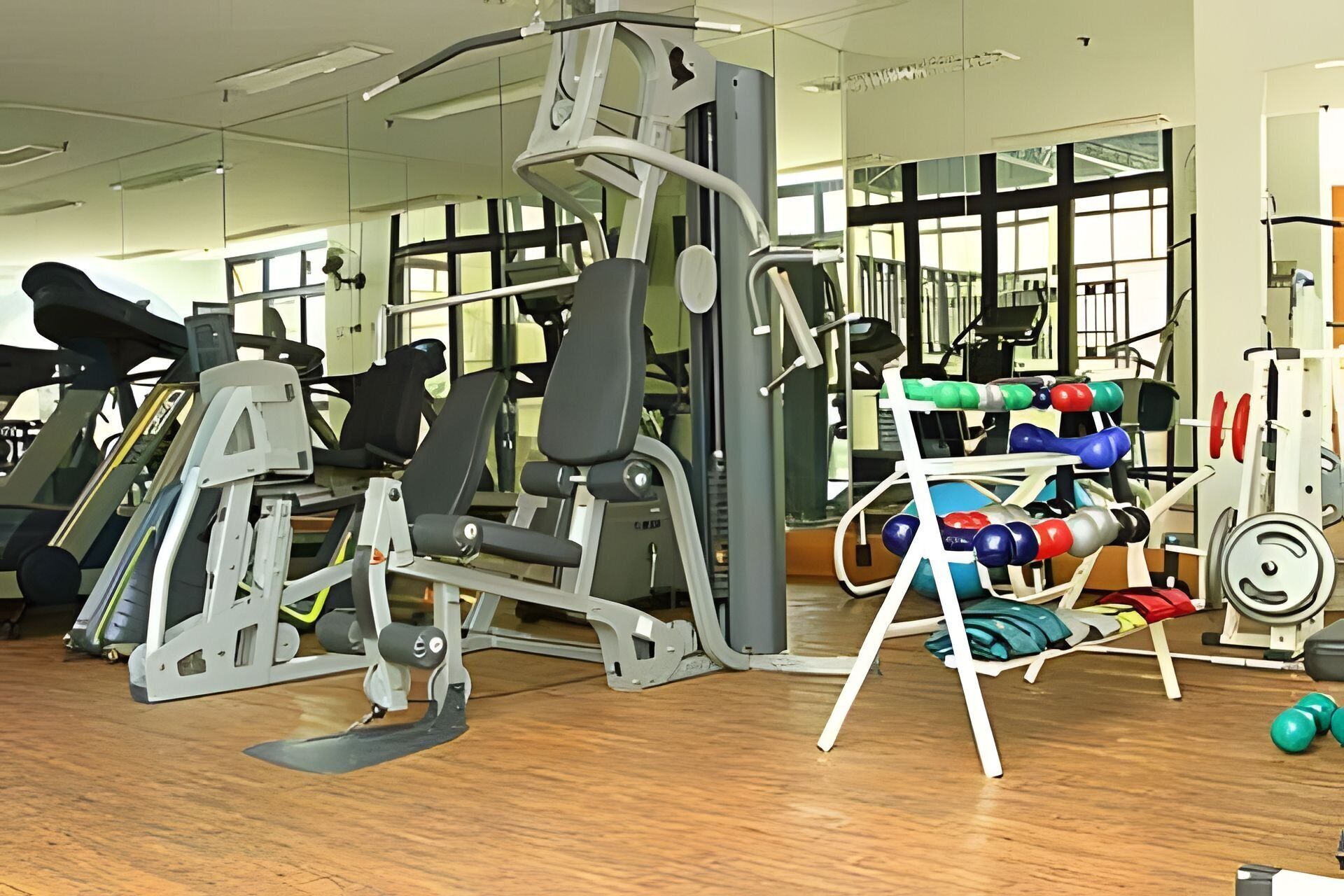 Una sala de gimnàstica amb equip d'exercici, prestatges per a peses i un mirall.