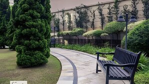 A curved pathway with a bench, surrounded by well-maintained hedges and trees. - Studio Living Mercure Pinheiros (São Paulo)