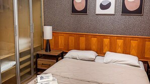 A hotel room with a bed, a wardrobe, and three abstract paintings on the wall. - Studio Living Mercure Pinheiros (São Paulo)