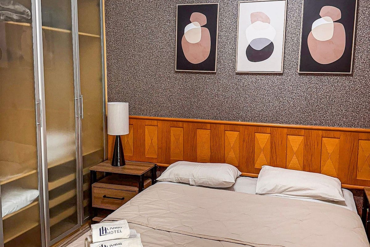 Une chambre d’hôtel avec un lit, une armoire et trois tableaux abstraits accrochés au mur.
