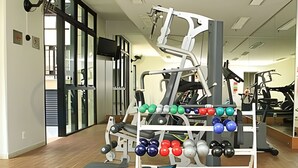 A gym with exercise equipment, including dumbbells and benches. - Studio Living Mercure Pinheiros (São Paulo)