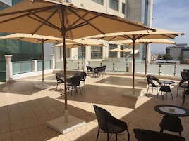 Terraza en la azotea con mobiliario exterior, incluyendo mesas y sillas, y grandes sombrillas que brindan sombra.