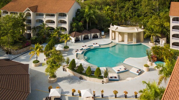 A resort with a large pool, multiple lounge areas, and a building with balconies.
