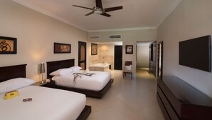 A hotel room with two beds, a ceiling fan, a TV, and a bathroom with a bathtub.