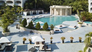 A resort with a large pool, lounge areas, and a building with multiple balconies.