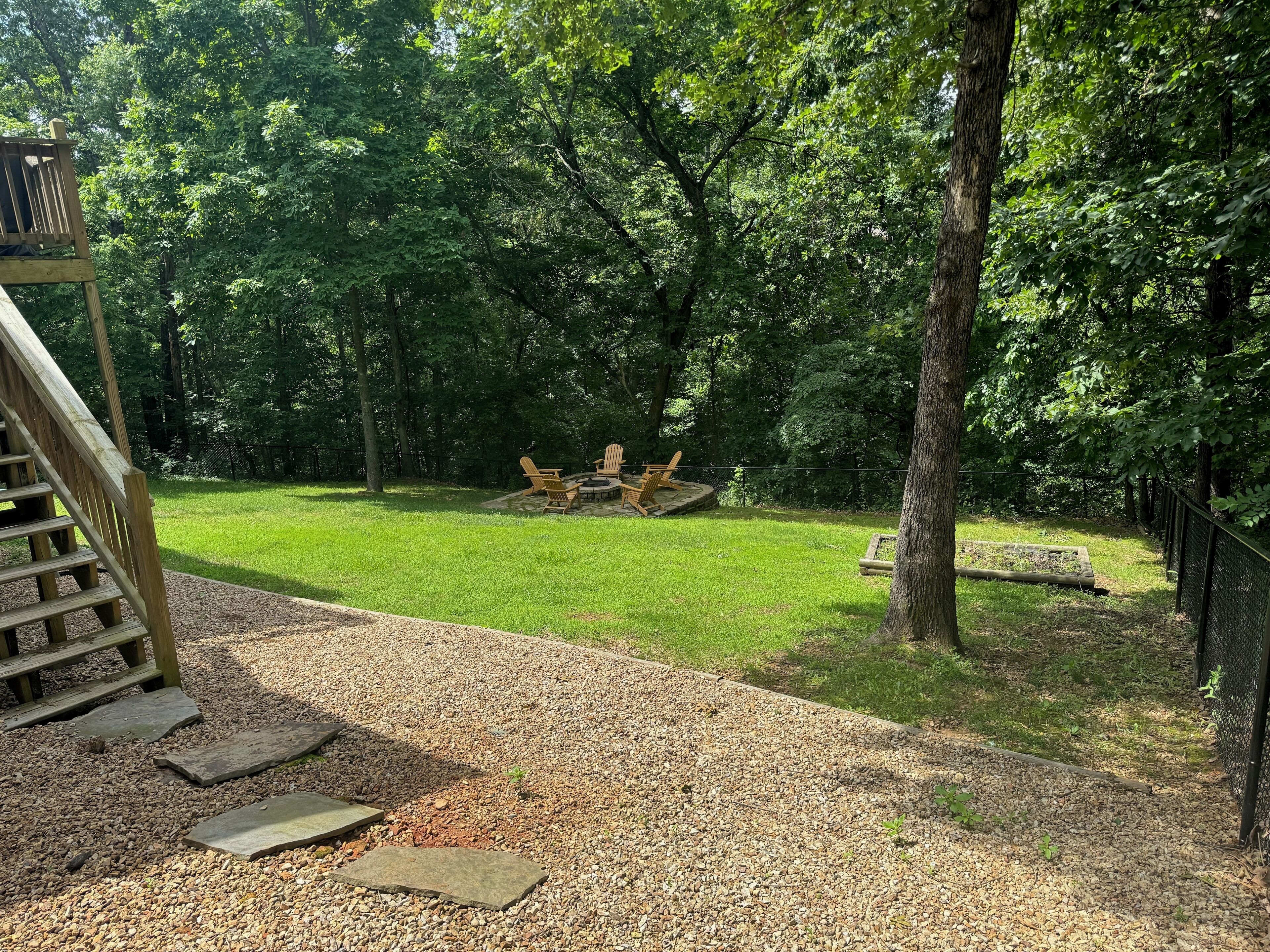 A backyard with a wooden deck, a fire pit, and outdoor furniture.