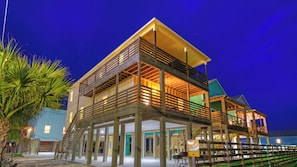 A waterfront property with a multi-level wooden deck, a covered outdoor area, and a visible entrance.