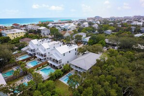 A residential area with multiple houses, a large white building with a swimming pool, and a view of the ocean. - Dolphin Days by Avantstay Pool, 0.2mi to Beach! (Destin)