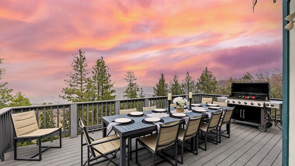 An outdoor deck with a dining table set for six, surrounded by chairs, and a grill. - 6bdr Group Retreat, Decks w/ Incredible Views Starry Heights by Avantstay (Lake Arrowhead)