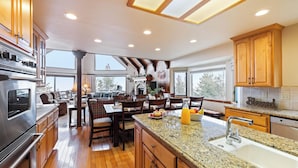 A spacious kitchen with granite countertops, wooden cabinets, and a large island. - 6bdr Group Retreat, Decks w/ Incredible Views Starry Heights by Avantstay (Lake Arrowhead)