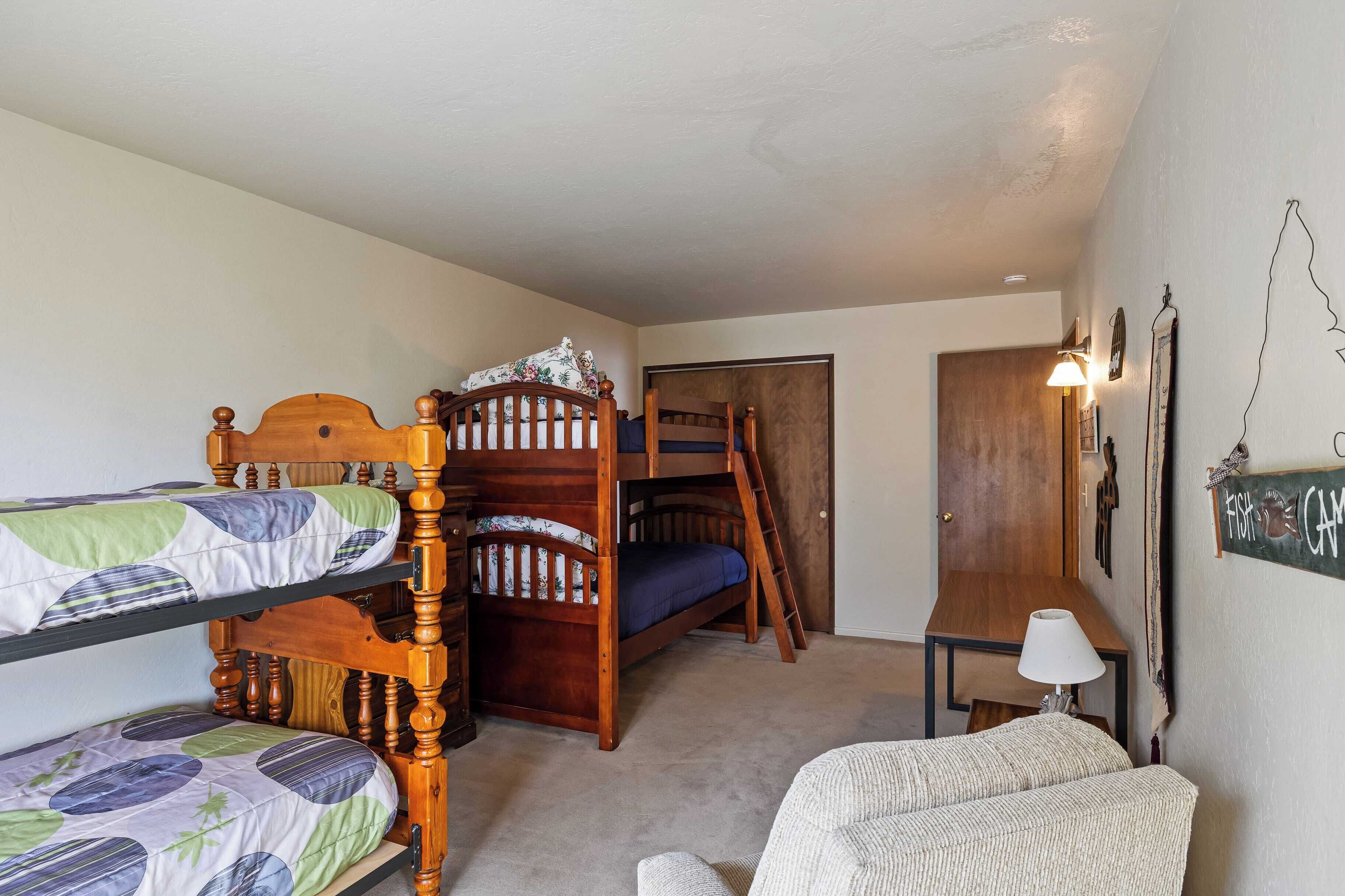 Une chambre avec un lit superposé, une échelle en bois, une petite table avec une lampe et un cadre photo fixé au mur.