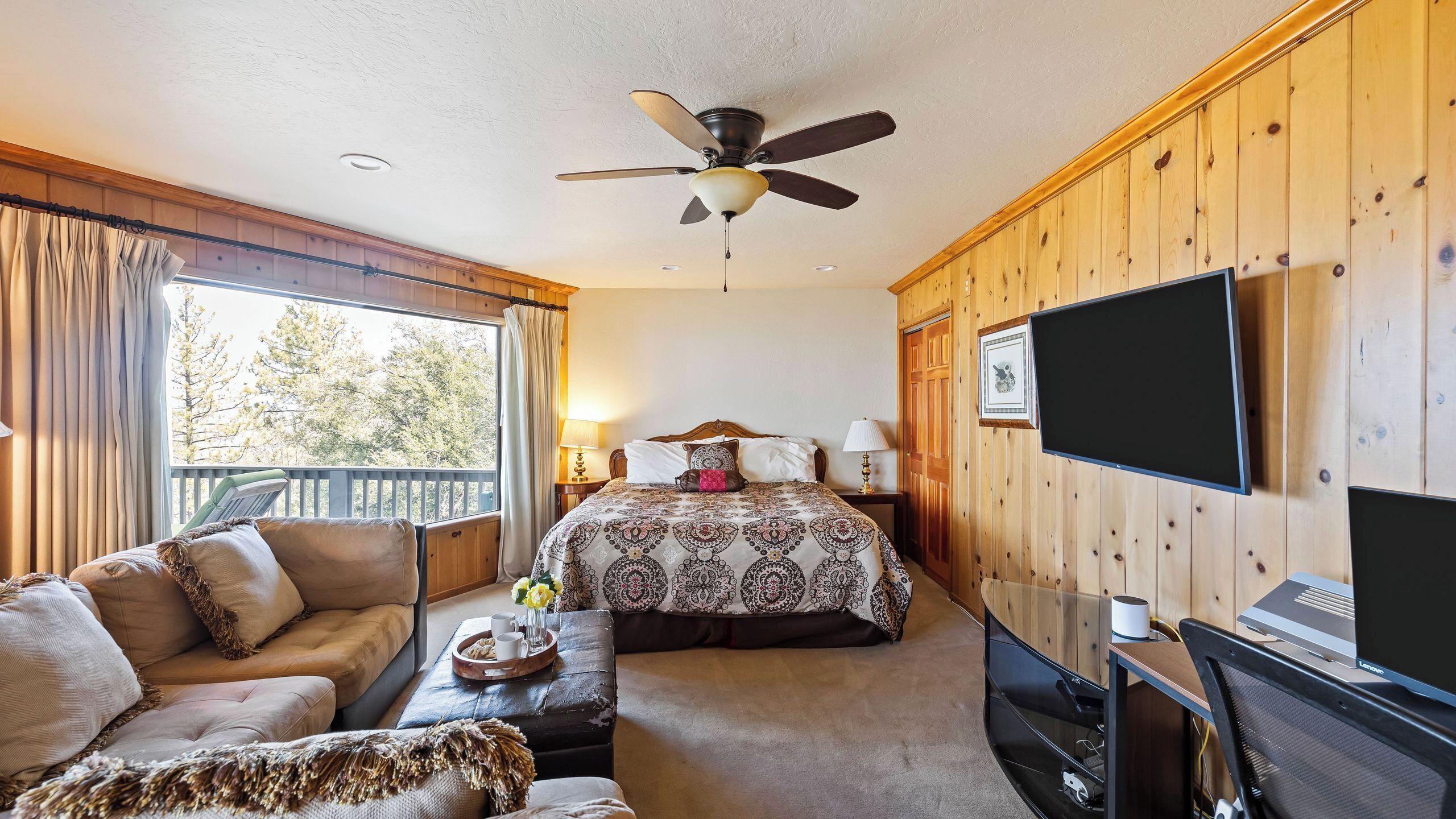 A bedroom with a bed, a television, a desk, and a chair.