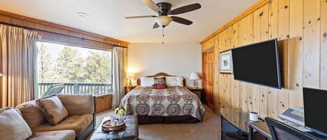 A bedroom with a bed, a television, a desk, and a chair.