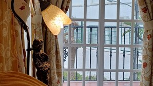A room with a glass table, a lamp, and curtains with a floral pattern.