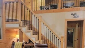 A wooden interior with a staircase, two leather chairs, and a lamp. - Brand New Luxury Cabin 5 minutes to TIEC
 (Tryon)