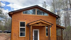 A log cabin with a front porch, a door, and two windows. - Brand New Luxury Cabin 5 minutes to TIEC
 (Tryon)