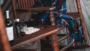 A wooden rocking chair with a colorful blanket, a bottle of wine, and a glass on a wooden table. - Panoramic View, Catskill Mountain Agri-Cabin (Gilboa)