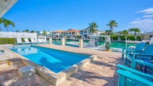 Una piscina amb gandules, un vaixell i vistes a cases i palmeres.