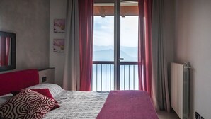 Une chambre à coucher avec un lit, une fenêtre avec des rideaux, un radiateur et un mur orné d’un tableau.