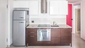 Une cuisine moderne dotée d’un réfrigérateur en acier inoxydable, de meubles blancs et d’un lave-vaisselle.