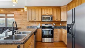 A modern kitchen with wooden cabinets, stainless steel appliances, granite countertops, and a built-in oven.