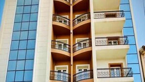A hotel with a central atrium, balconies, and a sign indicating it is a hotel and restaurant. - Rue d'Or (Setif)