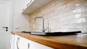 Eine Küche mit Holzarbeitsplatte, Spüle aus Edelstahl und beige gefliestem Fliesenspiegel.