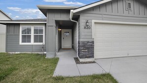 Una casa residencial con garaje, puerta de garaje con el número 820 y entrada principal con puerta y pequeño porche.