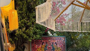 A cozy outdoor seating area with wicker furniture, a colorful rug, and a macramé hanging light fixture. - Andoya Pension (Bodrum)