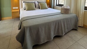 A hotel room with a large bed, a headboard, a bedside table, a lamp, a wall-mounted air conditioner, a window with curtains, and a view of buildings outside. - Andoya Pension (Bodrum)