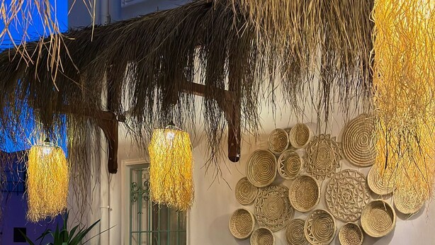 An outdoor dining area with round tables covered in green tablecloths, wicker chairs, and hanging light fixtures. - Andoya Pension (Bodrum)