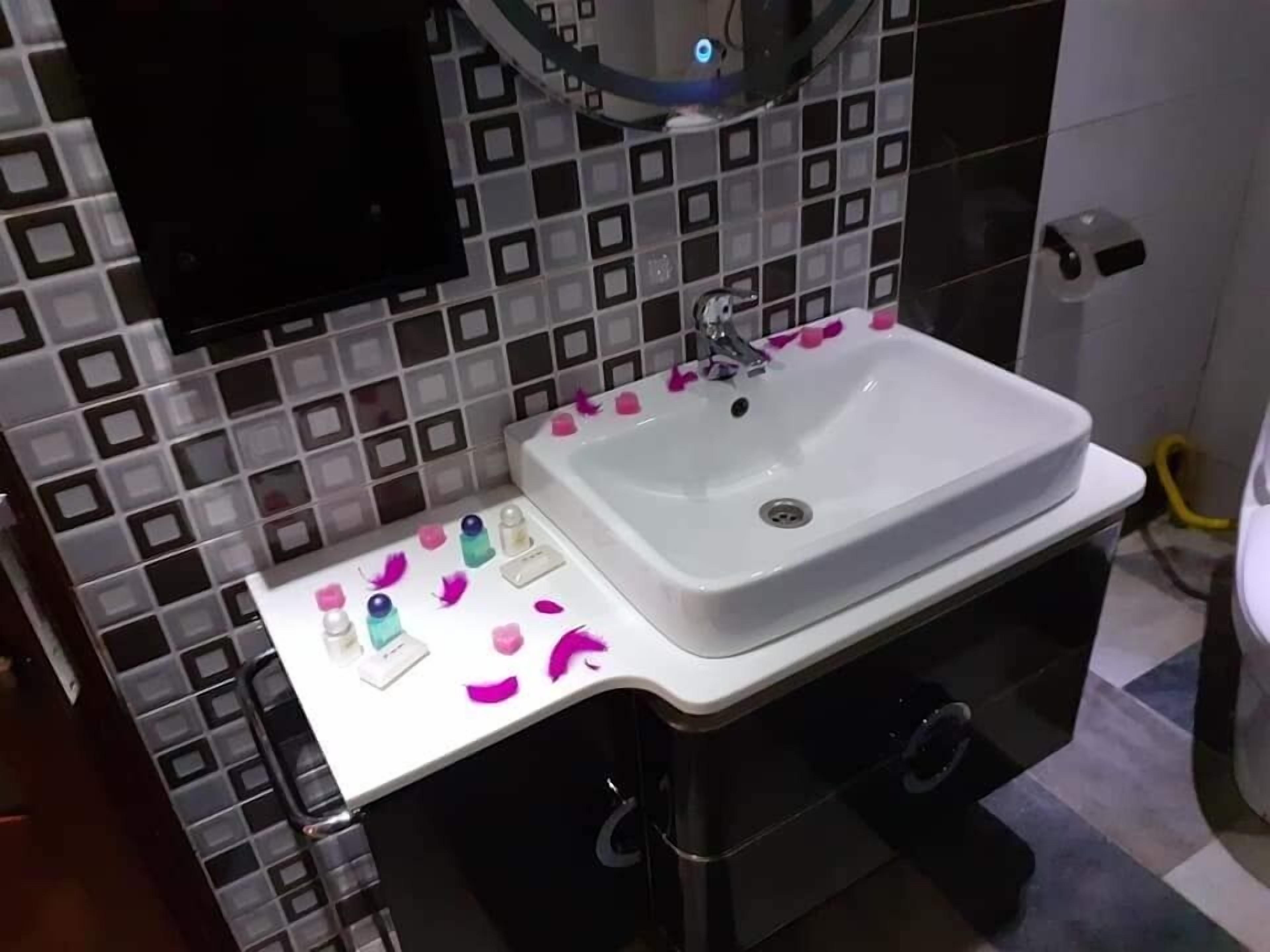 A bathroom with a white sink, black and white tiled backsplash, and a mirror above the sink.