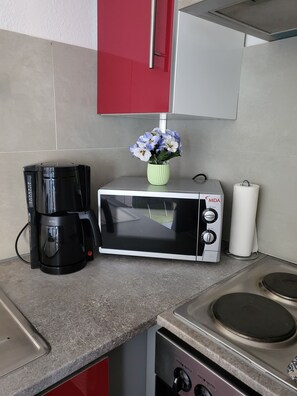 A kitchenette with a coffee maker, a microwave, and a gas stove. - Ferienwohnung Rosenhirsch (Altenau)