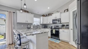 A modern kitchen with white cabinets, a granite countertop, and a black refrigerator. - Luxury 4 bed 2.5 bath home TF (Twin Falls)